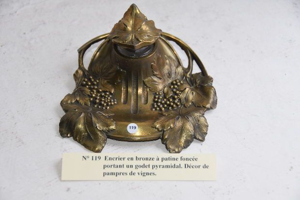 Encrier en bronze à patine foncée portant un godet pyramidal. Décor de pampres de vignes.